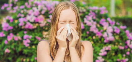 Woman sneezing outdoors in the springtime