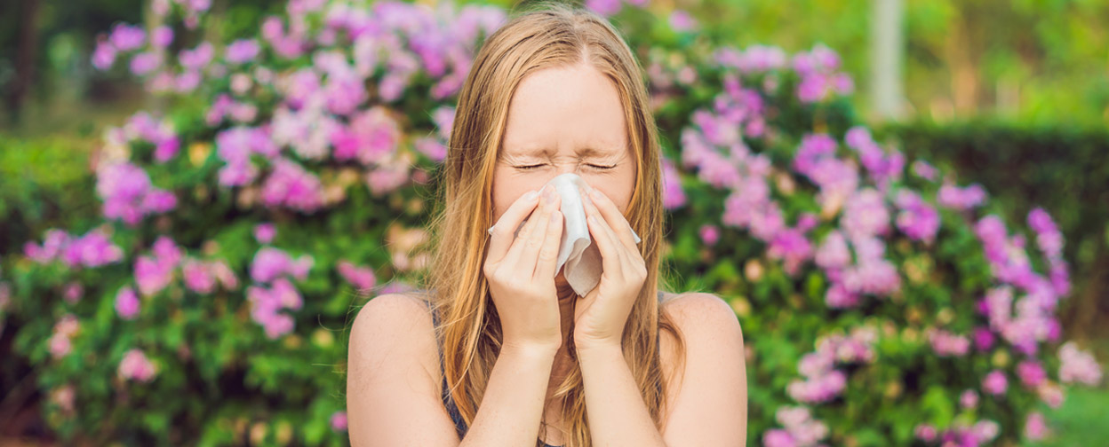 Woman sneezing outdoors in the springtime