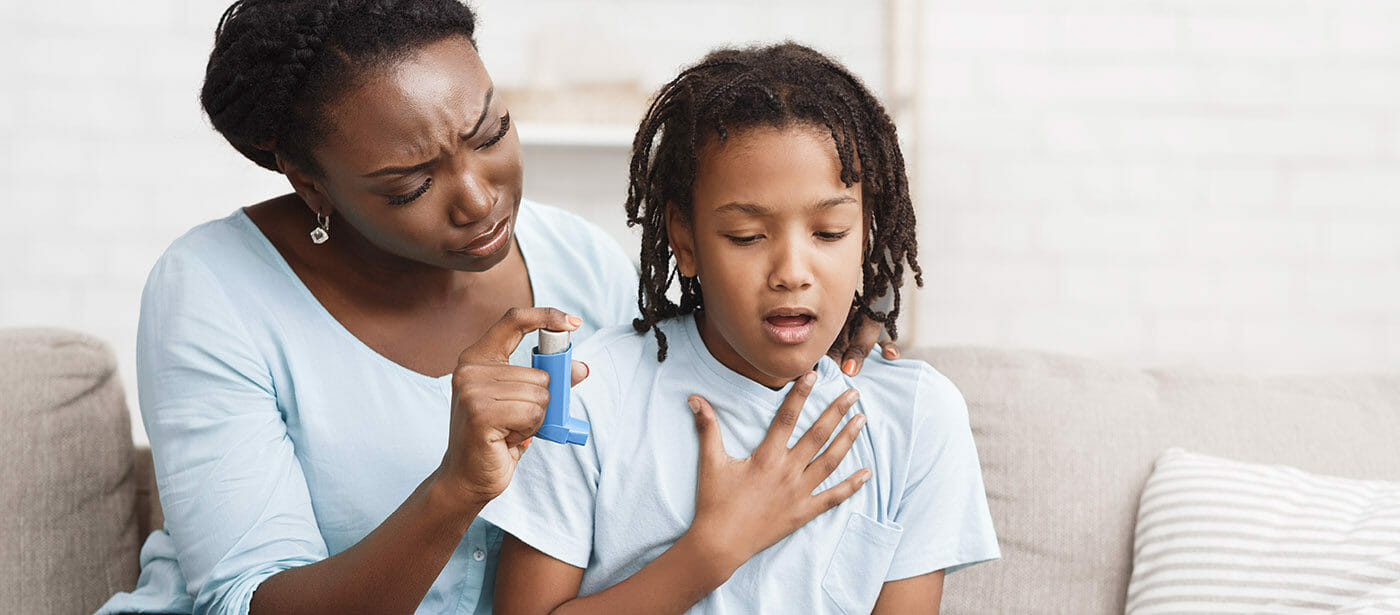 Mother holding asthma inhaler for daughter
