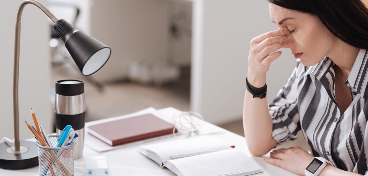 Woman experiencing workplace allergy symptoms at desk